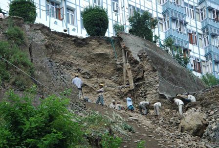 Workers clearing the debris after a portion of road had collapsed near High court in Shimla on Tuesday. The private building of hotel in danger due to caved in wall.Photo toi