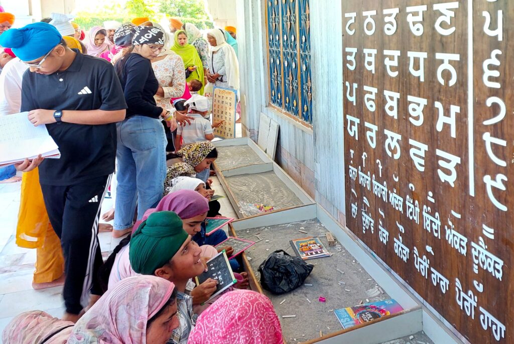 Children write Gurmukhi alphabets on slates in Gurdwara Likhansar Sahib.